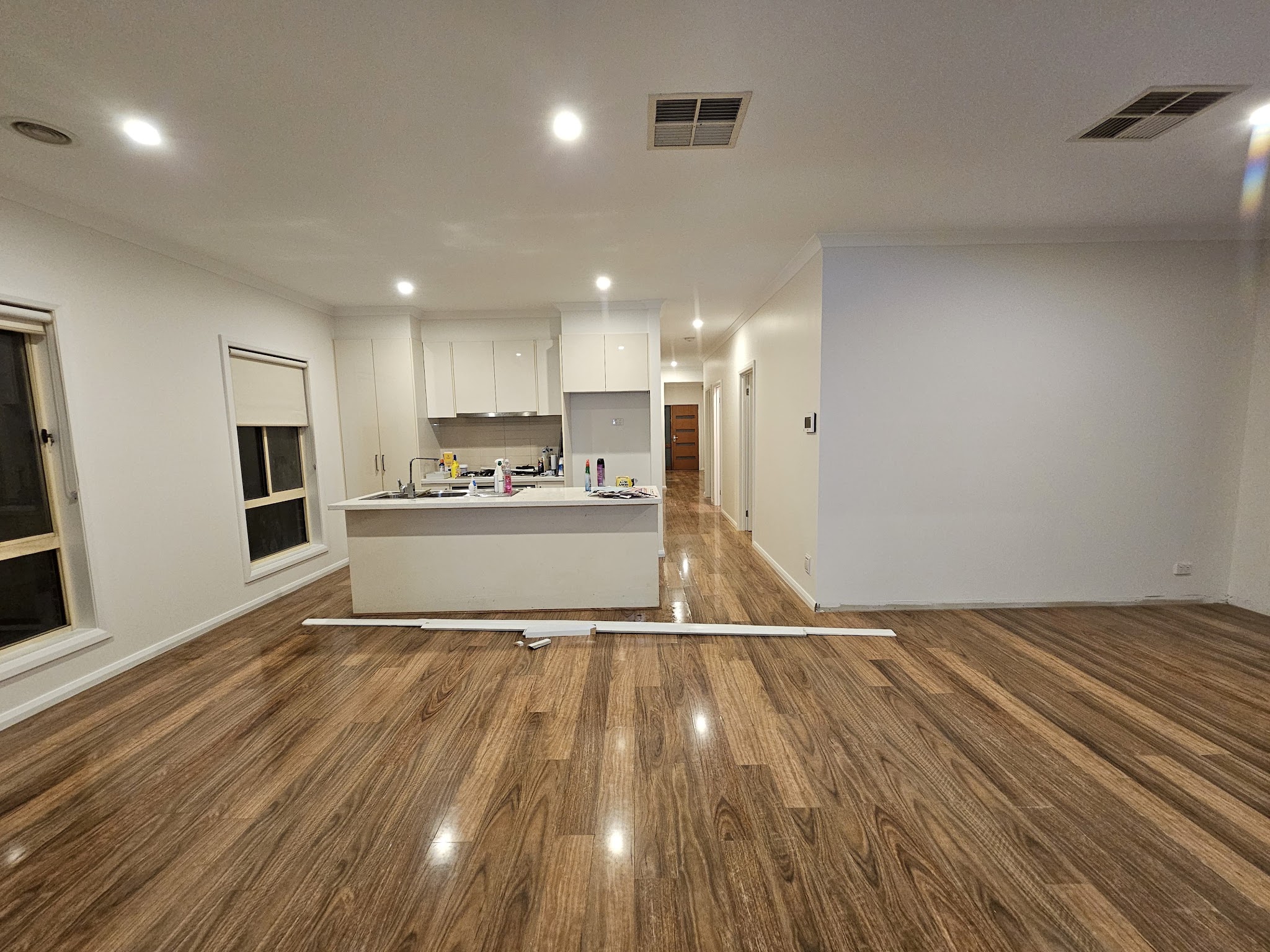 Freshly painted open plan kitchen and living area with white walls and cabinetry
