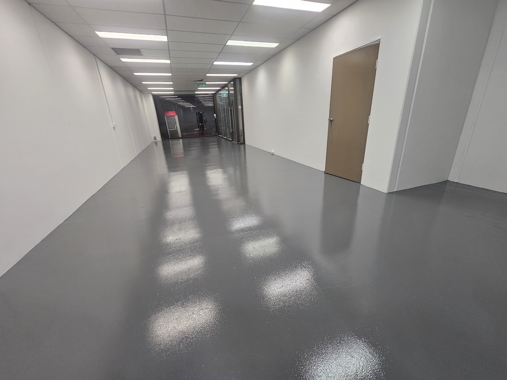 Commercial corridor with a glossy grey epoxy floor and freshly painted white walls