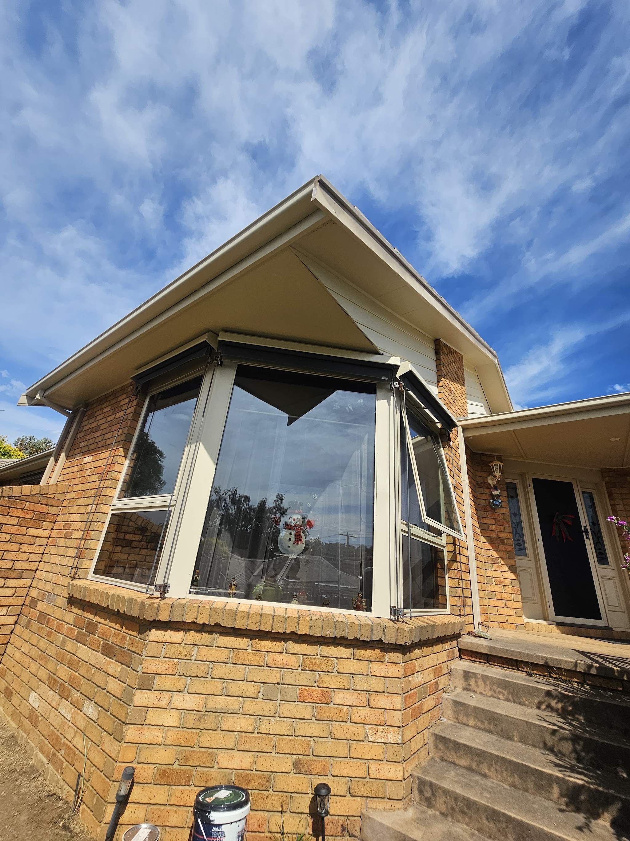 Brick home with freshly painted cream eaves and fascia under a blue sky