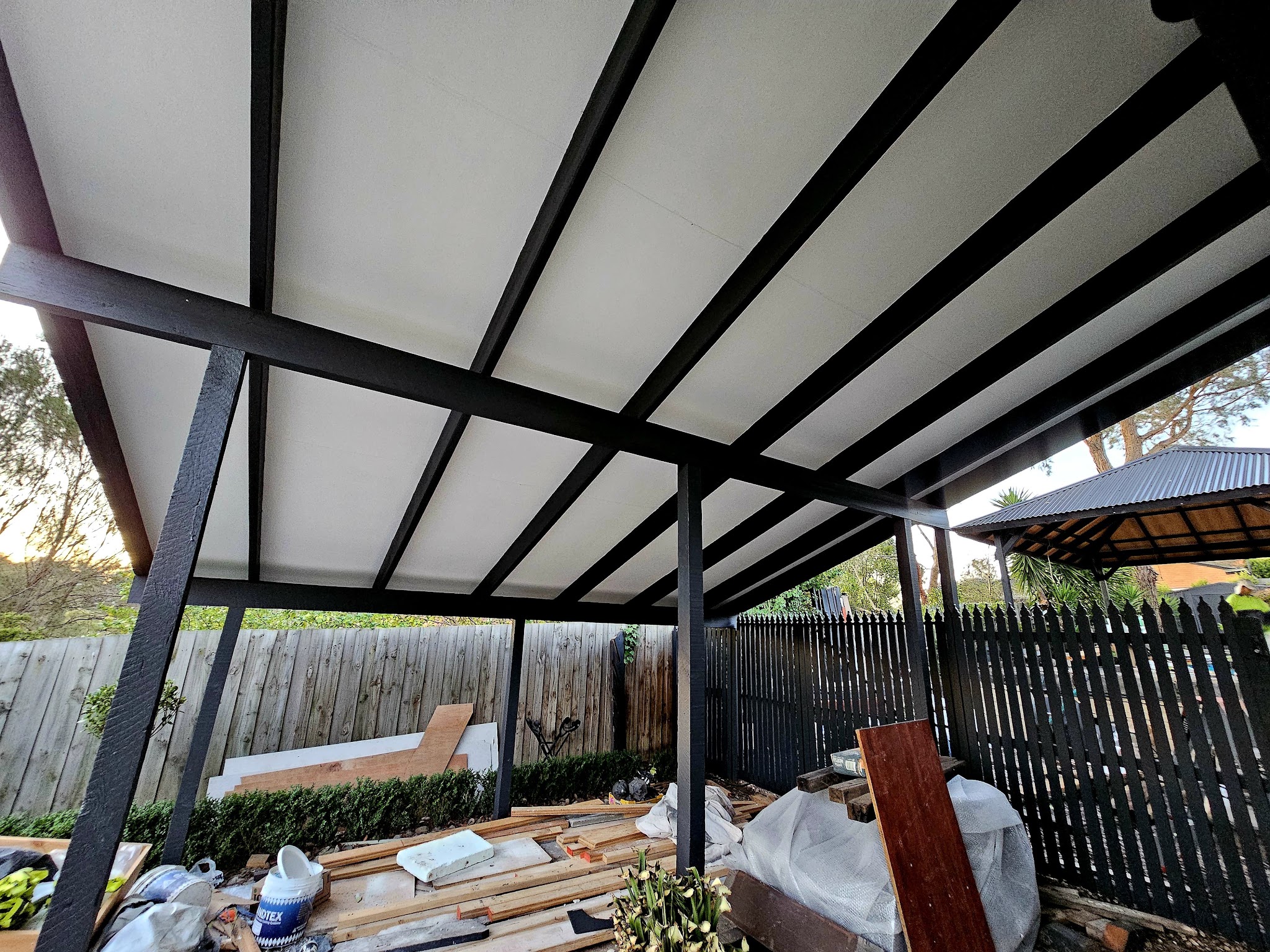 Underside of a pergola with freshly painted charcoal beams and white lining